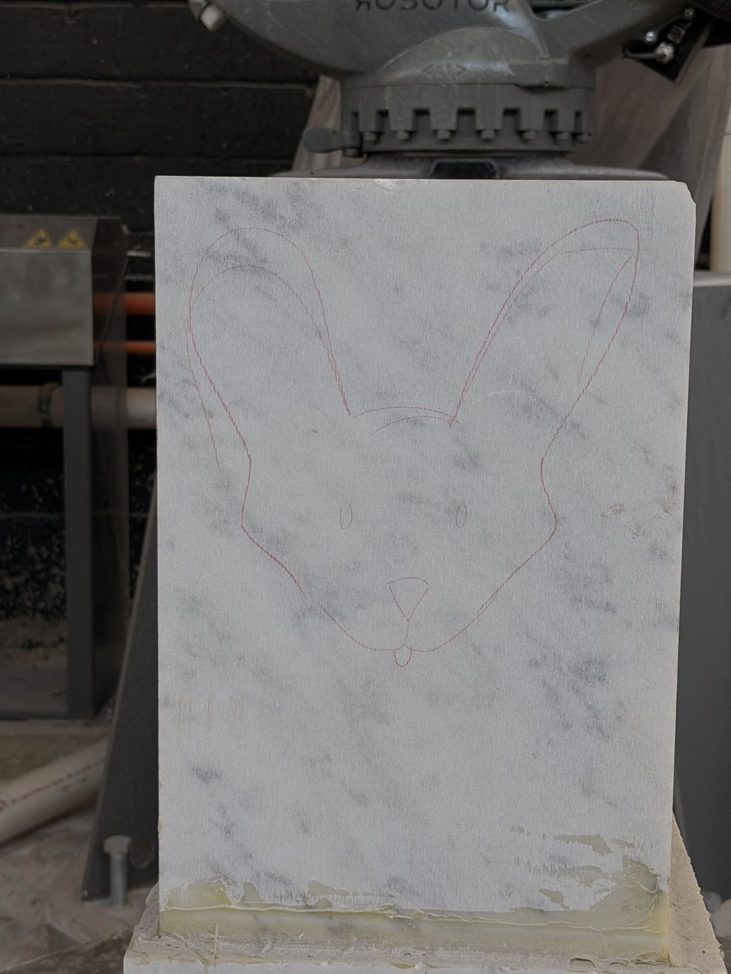 Raw marble block with the bunny outline sketched on it.